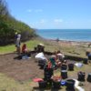 archeologists excavating with the sea in the background