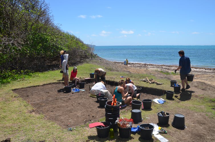 archeologists excavating with the sea in the background
