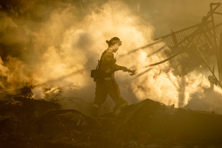 A firefighter walks near the smoldering remains of homes during a fire that reached San Bernadino, California, in 2019.