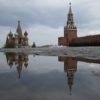 the Kremlin's Spasskaya Tower and St. Basil's Cathedral reflected in rain water puddles in Red Square in Moscow, Russia