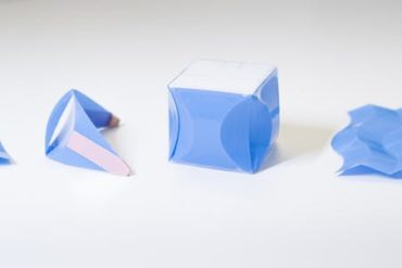 Four small plastic sheets with curved folds forming different structures