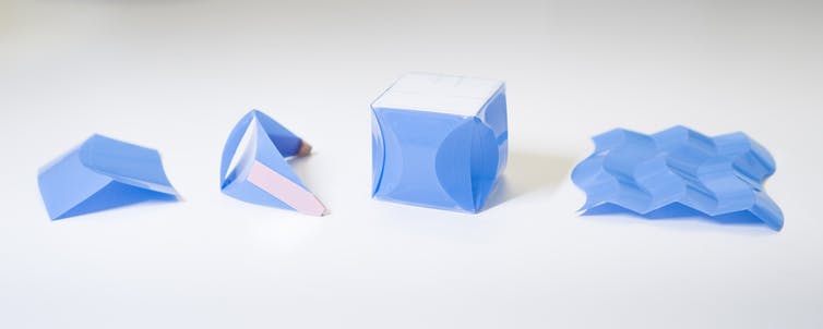 Four small plastic sheets with curved folds forming different structures
