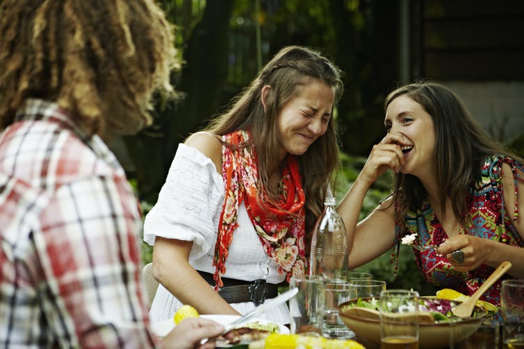 women laughing together at an outdoor meal
