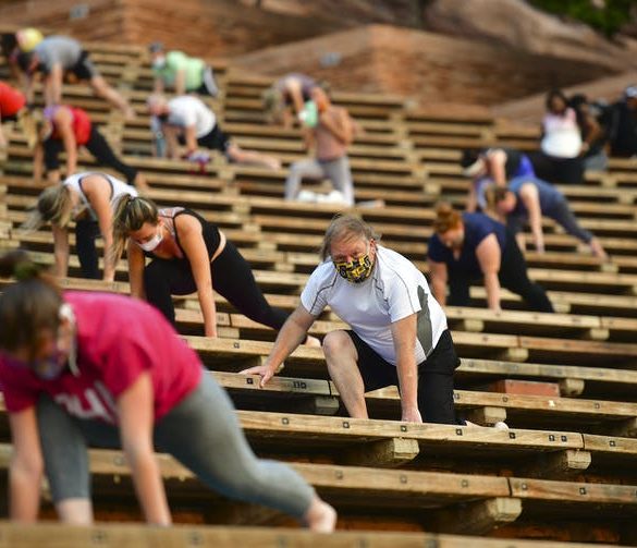people stretching while socially distanced in stadium seats