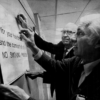 Two 1970s era older male politicians posting a sign that reads 'For your health and safety and the comfort of others, no smoking.'