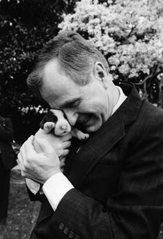 George H.W. Bush cuddles a very young puppy.