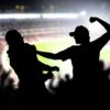 Fight in a football game crowd. Angry man hitting another spectator in soccer match audience. Violent argument between two fans of different teams and clubs.