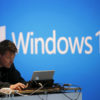 A man works on a laptop computer near a Windows 10 display at Microsoft Build in San Francisco