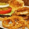 A hamburger and onion rings on a plate.