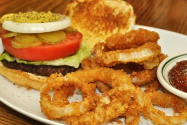 A hamburger and onion rings on a plate.