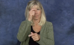 A woman holding her right hand to her eye and her left hand out in front of her with a pointed finger