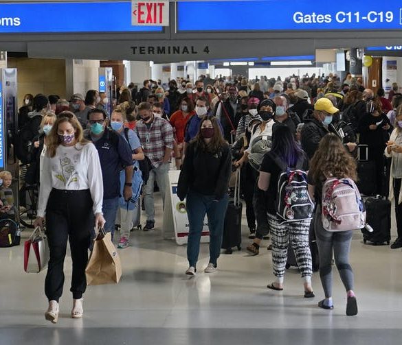 Masked passengers moving through airline terminal