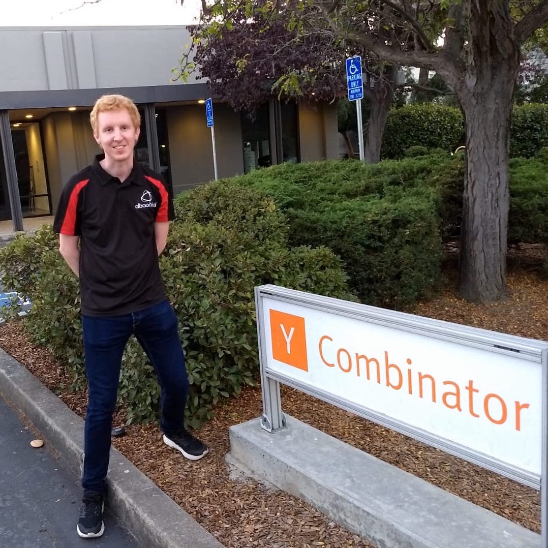 Alba Orbital founder Tom Walkinshaw next to a Y Combinator sign.
