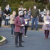 masked people stand outside in a socially distanced way