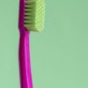 A magenta toothbrush with neon-green bristles.