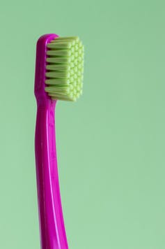 A magenta toothbrush with neon-green bristles.