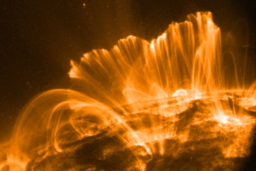 A photo of the surface of the Sun with a towering explosion of plasma.
