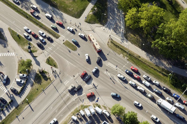 An aerial view of an intersection with cars making a left turn.