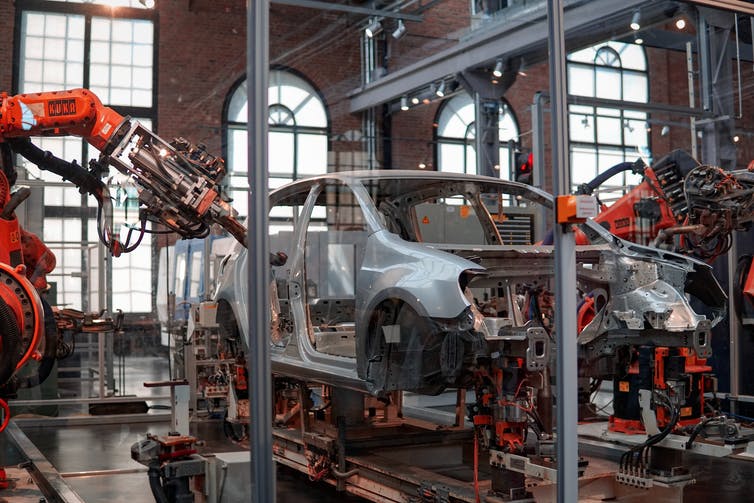 Robotic arms reach into the frame of a car being manufactured