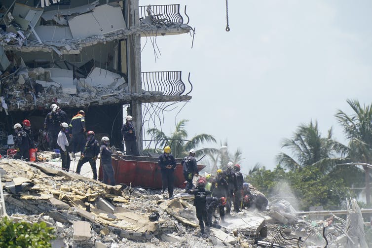 Emergency crews climbing over rubble.