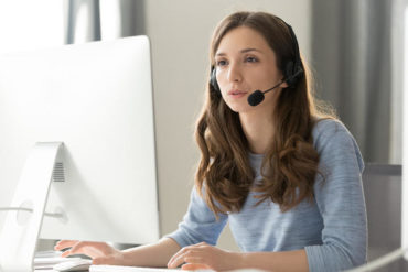 Businesswoman in headset call center agent consulting participating video conference