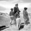 Three men and two boys stand on a dry landscape