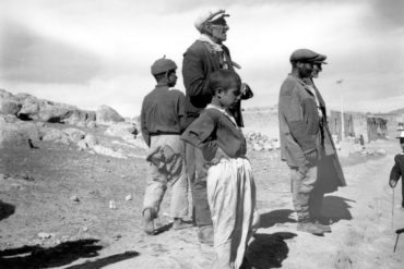Three men and two boys stand on a dry landscape