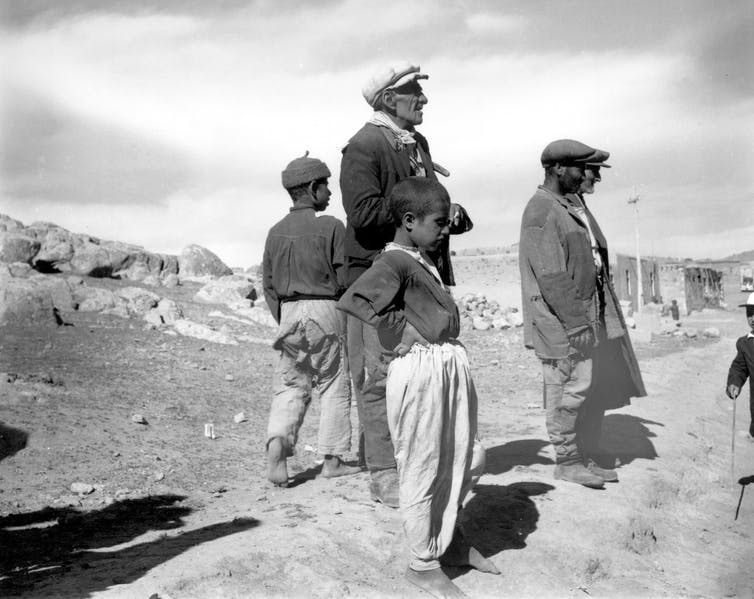 Three men and two boys stand on a dry landscape