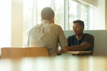 two seated men in discussion