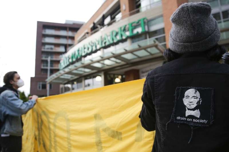 An image of Amazon founder and CEO Jeff Bezos is pictured on a jacket as people rally rally outside a Whole Foods Market in soli