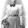 A black and white portrait of a young Emmy Noether in a shirt and a skirt.