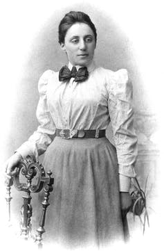 A black and white portrait of a young Emmy Noether in a shirt and a skirt.