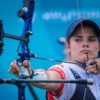 female archer pulls back the bowstring