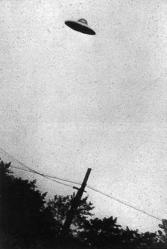 A grainy black and white photo showing a flying saucer in the sky.