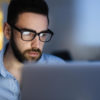 Computer user wearing glasses working with laptop