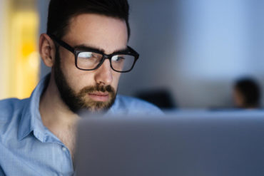 Computer user wearing glasses working with laptop