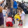 young girls masked at airport with luggage