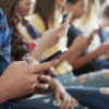 Close Up Of A Line Of High School Students Using Mobile Phones