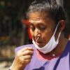 woman with lowered mask swabs her own nose