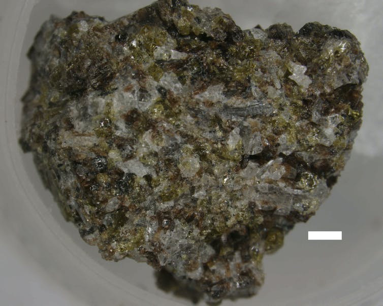 A blue-, white- and black-flecked rock in a white dish.