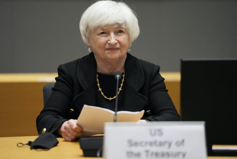 Janet Yellen sits at a table while holding a copy of speech in her hand