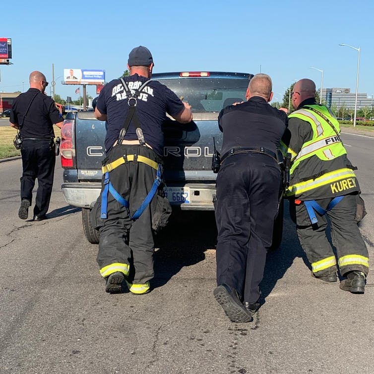 Firefighters and police offers move truck at crash scene