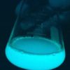 A glass beaker glowing with a bluish light.