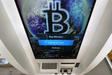 A Bitcoin ATM displays a bitcoin logo on the screen