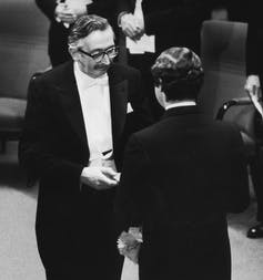 Hounsfield in tuxedo shaking hands with King facing away from camera