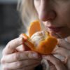 A woman with COVID-19 symptoms tries to sense the smell of a fresh tangerine.