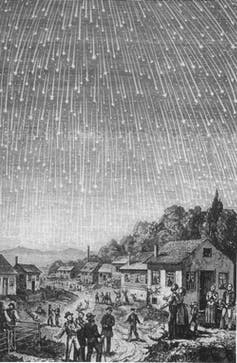 A black and white print of many streaks of light in the sky above a small town.
