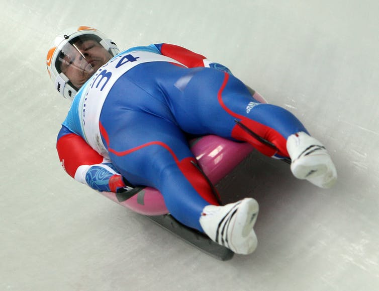 A luge racer lying on his back in an aerodynamic pose.