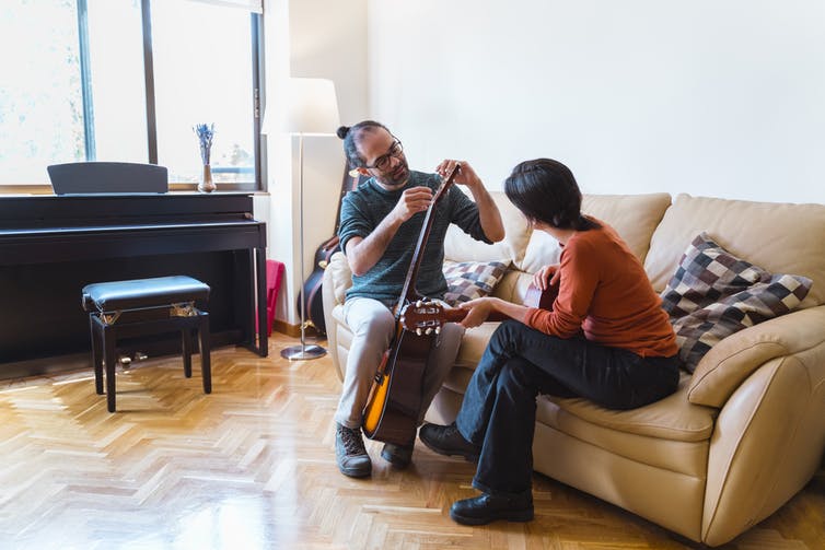 man and woman with musical instruments sit on couch