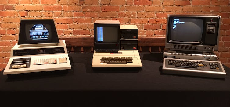 Three old personal computers sitting on a table.